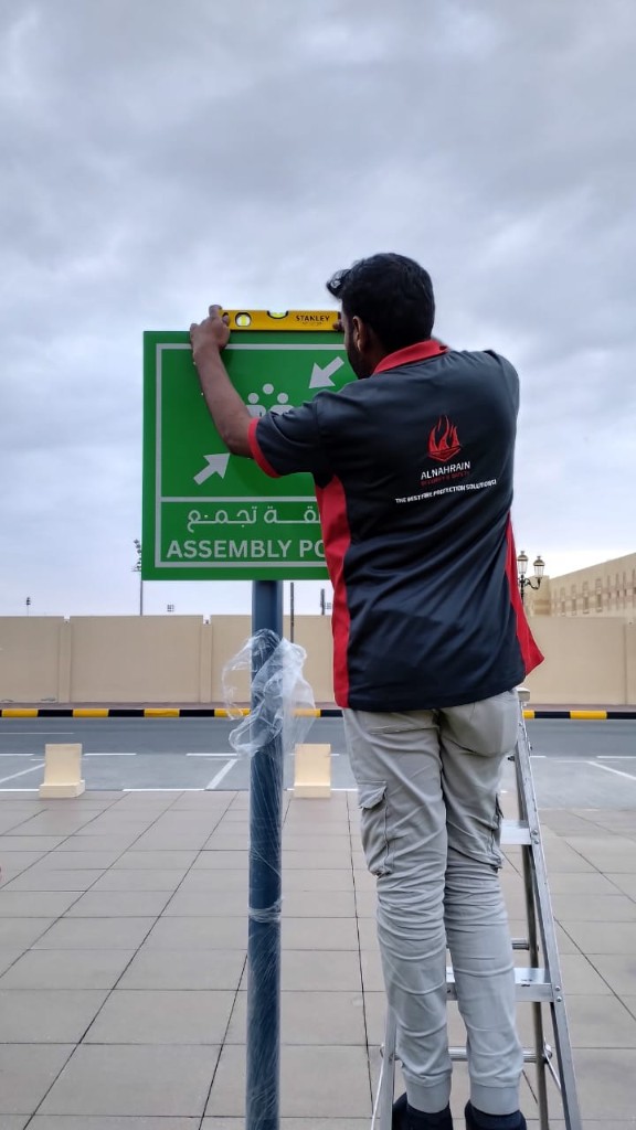 Alnahrain technician installing and leveling an assembly point sign